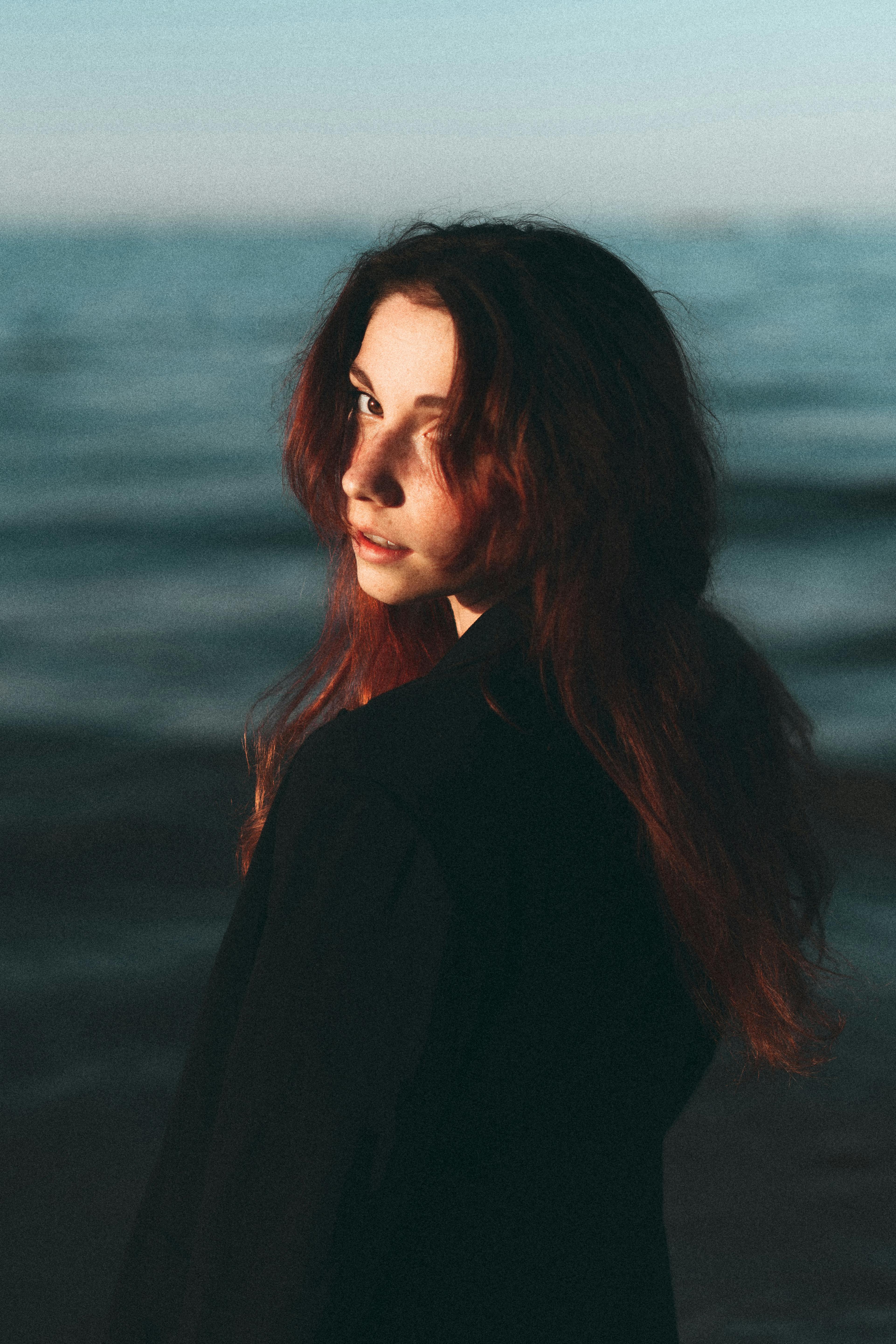 Woman with long dark hair standing by the ocean
