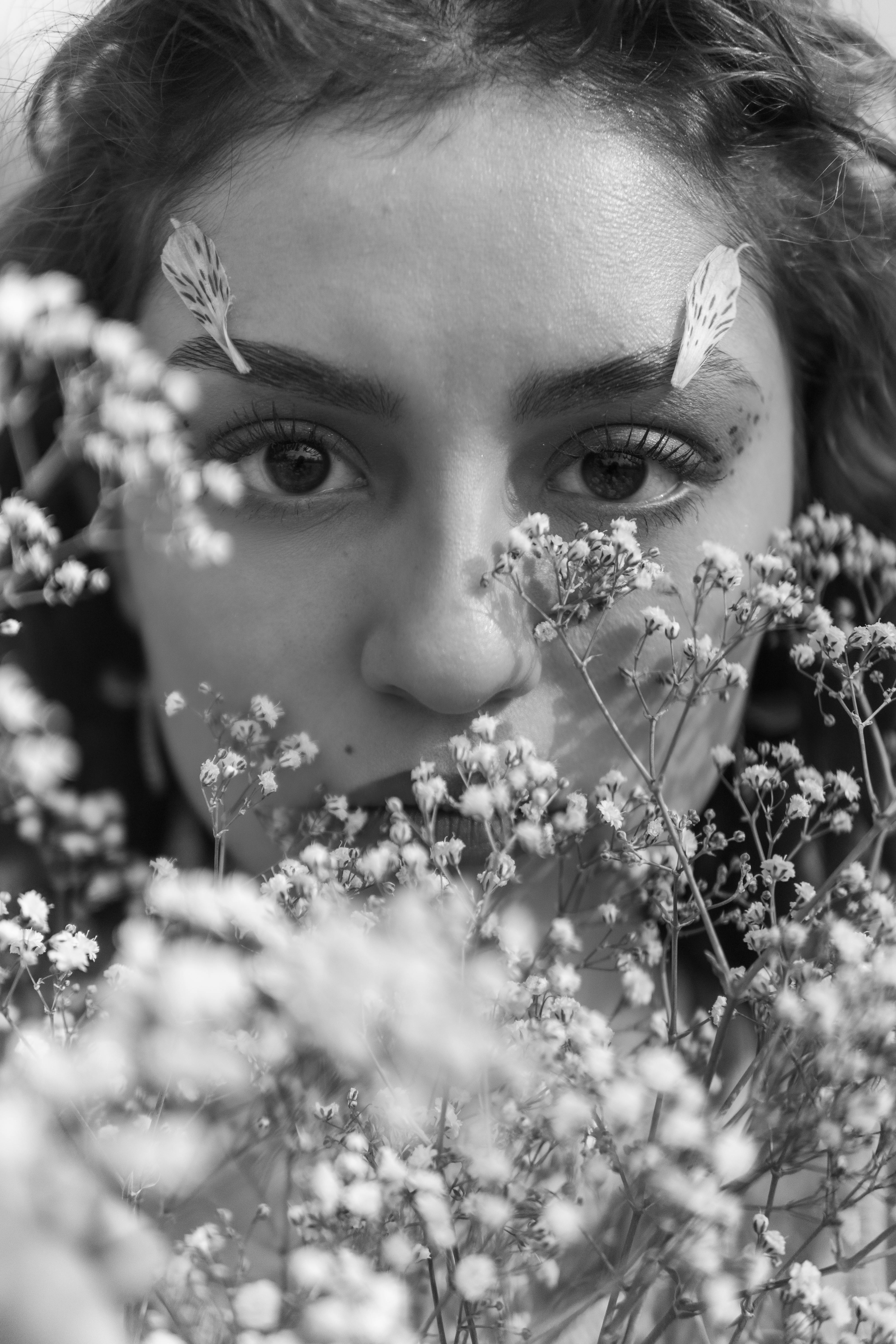 Black and white photo of a person with flowers in front of their face