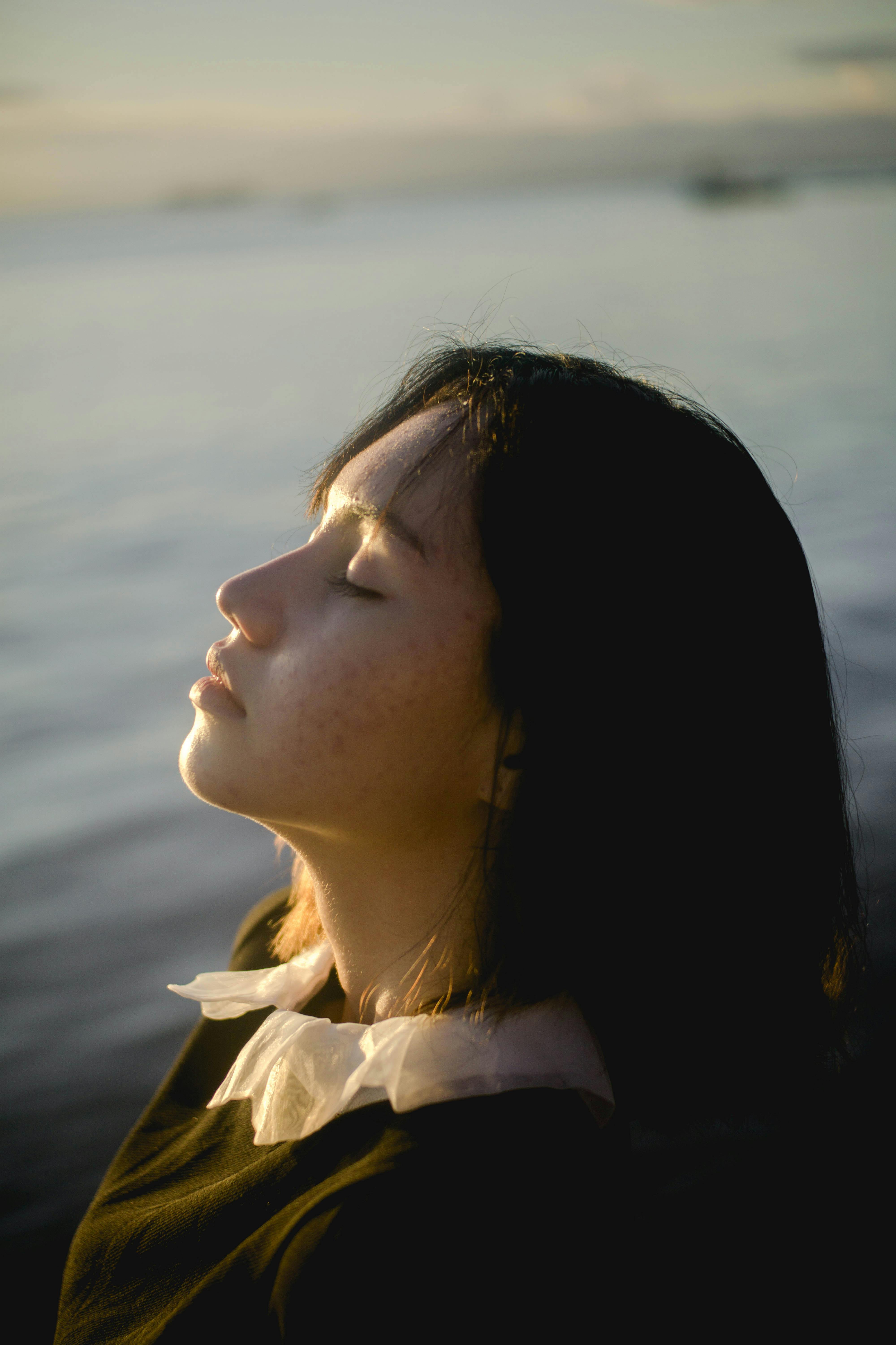 Woman with closed eyes against a blurred natural background